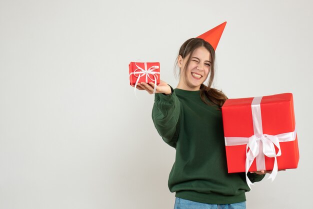 Niña feliz con ojos parpadeados sosteniendo sus regalos de Navidad en blanco