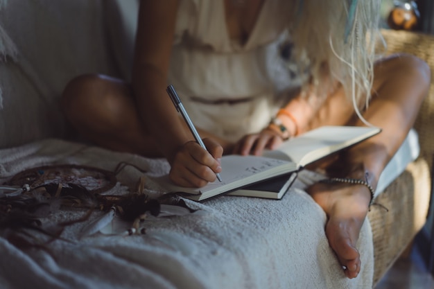 niña feliz pasa tiempo en casa en un interior acogedor, escribe y dibuja en un cuaderno.