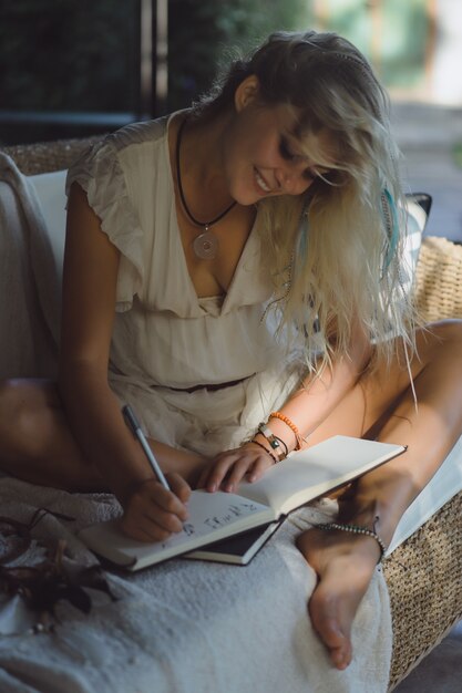 niña feliz pasa tiempo en casa en un interior acogedor, escribe y dibuja en un cuaderno.