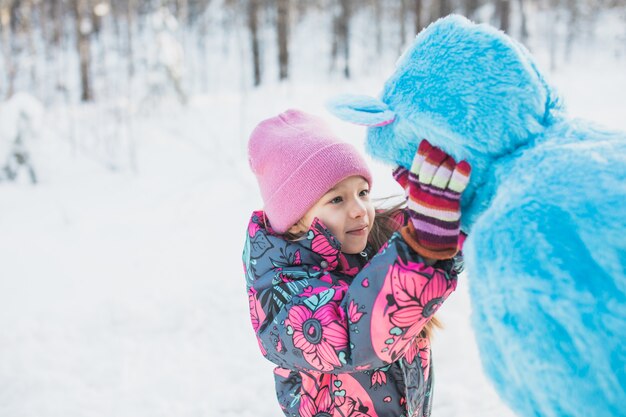 Niña feliz pellizcando las mejillas de una mujer en un traje azul esponjoso