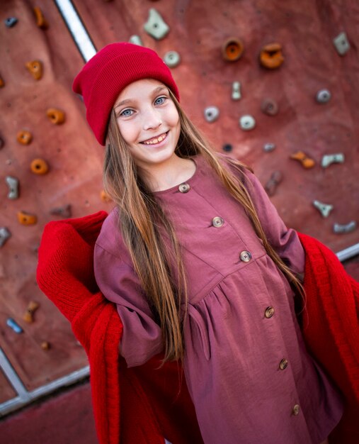 Foto gratuita niña feliz posando junto a un muro de escalada