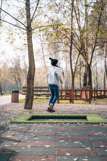 Foto gratuita niña feliz saltando en un pequeño trampolín en el parque