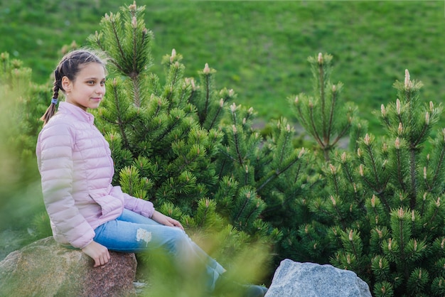 Niña feliz sentada en una roca