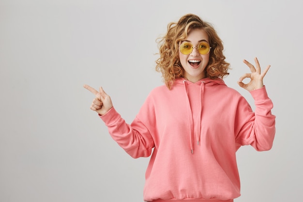 Niña feliz sorprendida apuntando a la izquierda, recomendar publicidad de producto, hacer un gesto bien