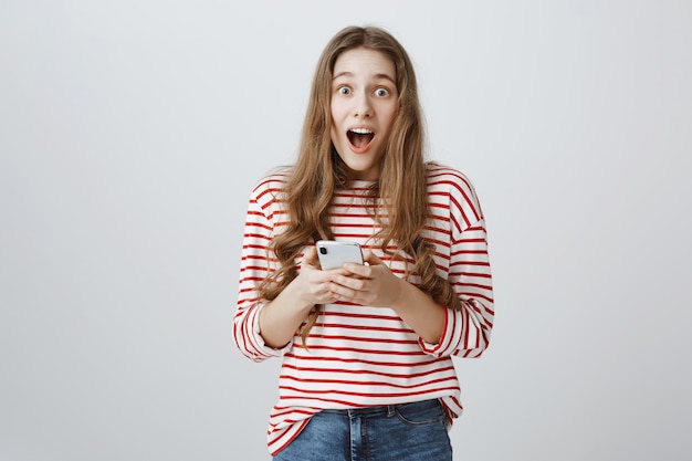 Niña feliz sorprendida reacciona a noticias increíbles en la alimentación del teléfono móvil