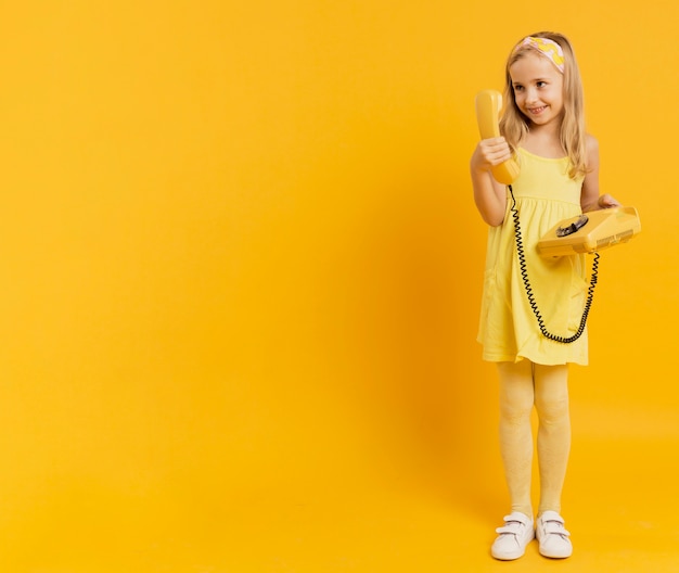 Niña feliz sosteniendo teléfono con espacio de copia