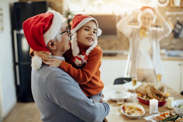 Foto gratuita niña feliz y su abuelo abrazándose mientras pasan el día de navidad juntos en casa