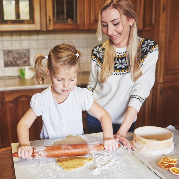 Niña feliz con su madre cocinar galletas.