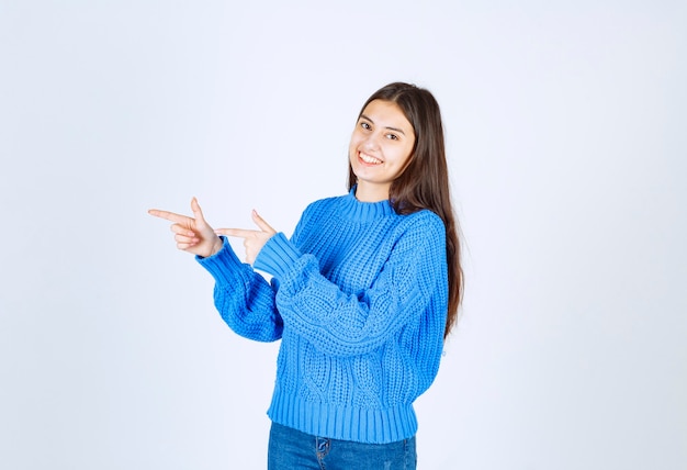 niña feliz en suéter azul de pie sobre blanco.