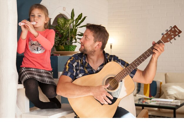 Niña feliz tocando la flauta junto a su padre