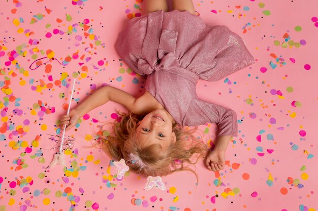 Niña feliz en traje de hada con confeti y varita