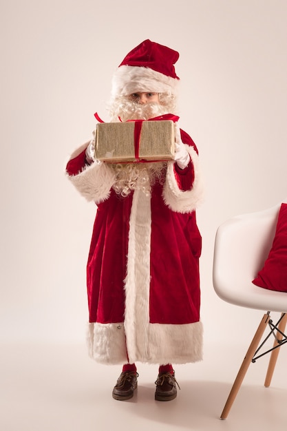 La niña feliz en traje de santa claus con caja de regalo