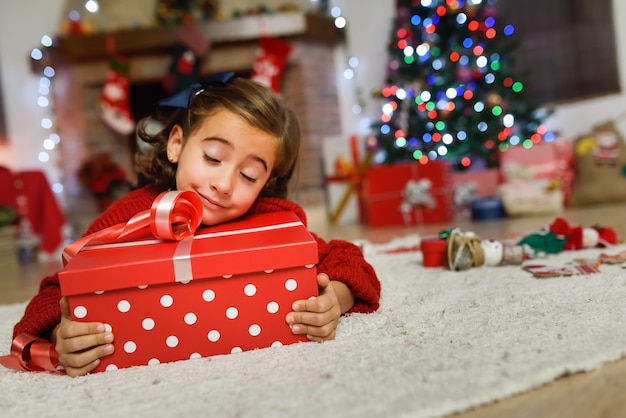 Niña feliz tumbada sobre un regalo