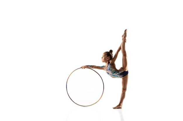 Niña flexible aislada en blanco. Pequeña modelo femenina como artista de gimnasia rítmica en leotardo brillante.