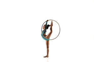 Foto gratis niña flexible aislada en blanco. pequeña modelo femenina como artista de gimnasia rítmica en leotardo brillante.