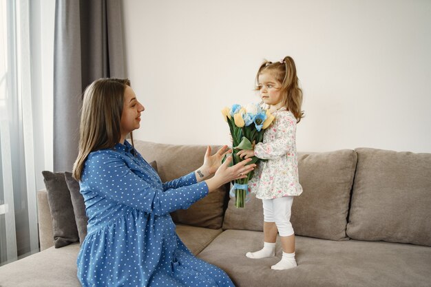 Niña con flores. Mamá está embarazada. Saludos para mamá.