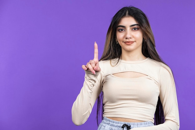 La niña se para con el fondo morado del hijo y señala con el dedo hacia arriba Foto de alta calidad