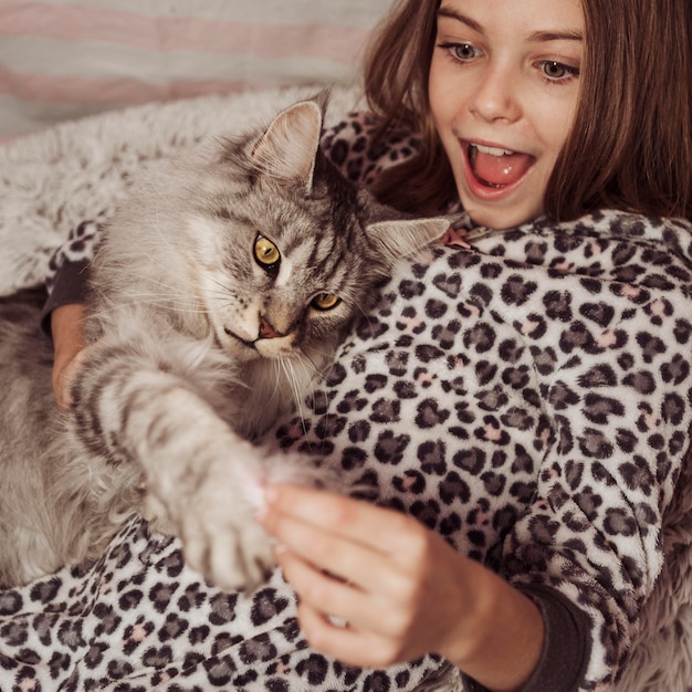 Niña y gato jugando en la cama