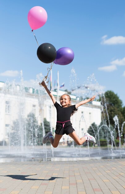 Niña con globos en fuente