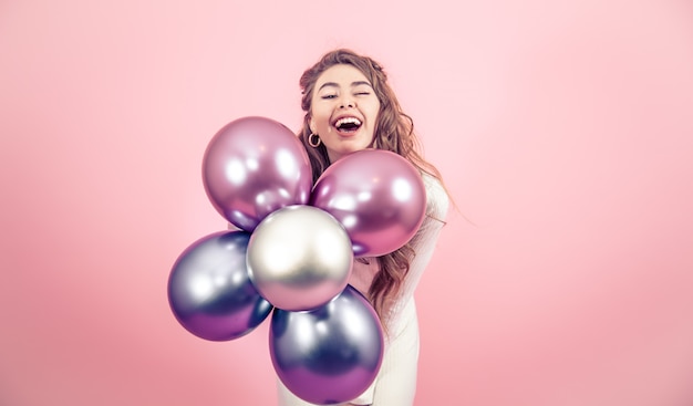 Foto gratuita niña con globos en una pared de color