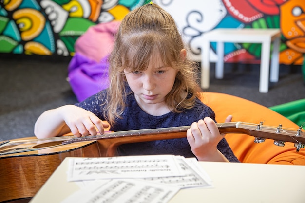 Foto gratuita una niña con una guitarra aprende solfeo, partituras y teoría musical