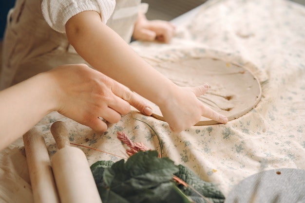 La niña hace un plato de arcilla y lo decora