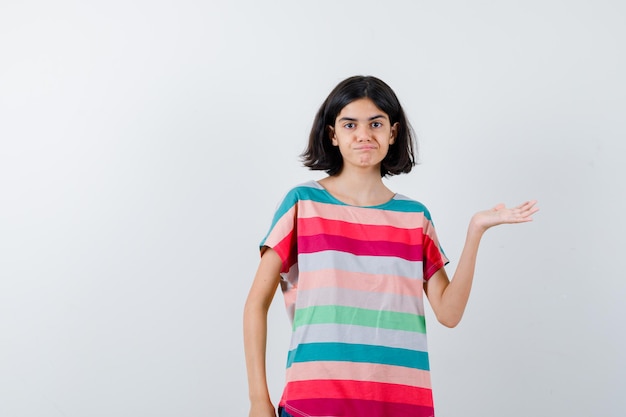 Niña haciendo gesto de bienvenida en camiseta y mirando confiado. vista frontal.