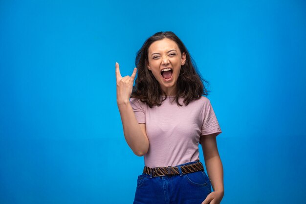 Niña haciendo el símbolo de la paz con los dedos y se ríe positivamente.