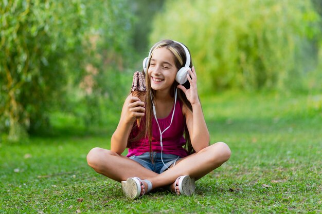 Niña con helado de chocolate y auriculares