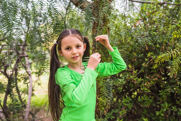 Niña hermosa que juega con la ramita que mira la cámara