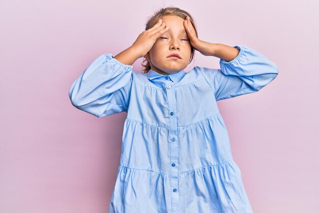 Niña hermosa con ropa informal con la mano en la cabeza, dolor de cabeza por estrés. sufriendo migraña.