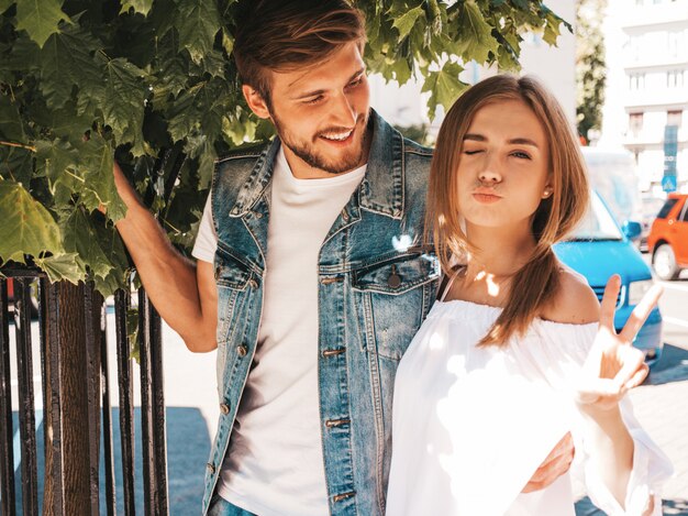 Niña hermosa sonriente y su novio guapo posando en la calle cerca del árbol.