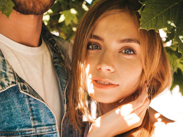 Niña hermosa sonriente y su novio guapo posando en la calle cerca del árbol.