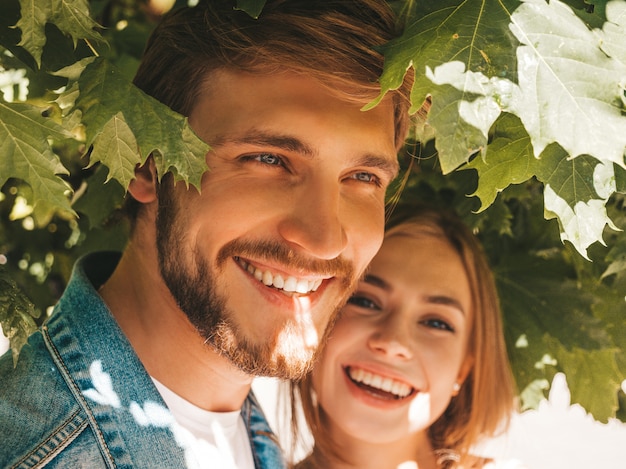 Niña hermosa sonriente y su novio guapo posando en la calle cerca del árbol.