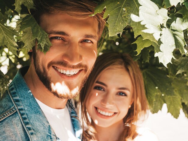 Niña hermosa sonriente y su novio guapo posando en la calle cerca del árbol.