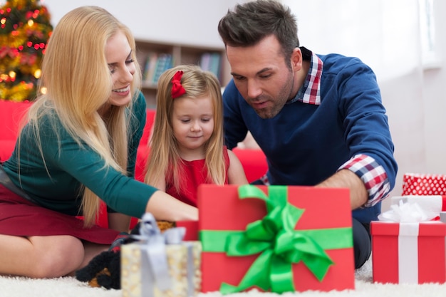 Niña impaciente abriendo regalos de navidad con los padres