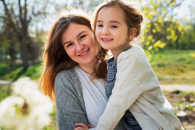 Niña inocente y madre posando al aire libre