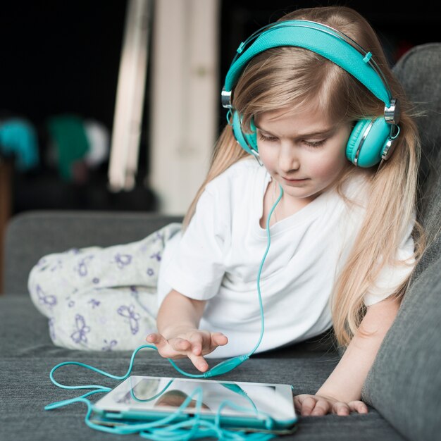 Niña joven con cascos de música y tablet