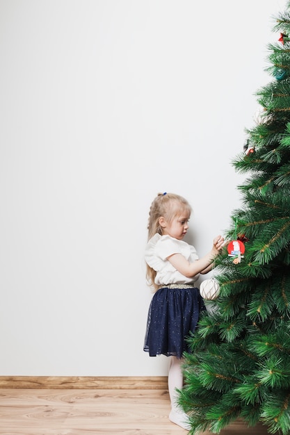 Niña joven decorando árbol de navidad