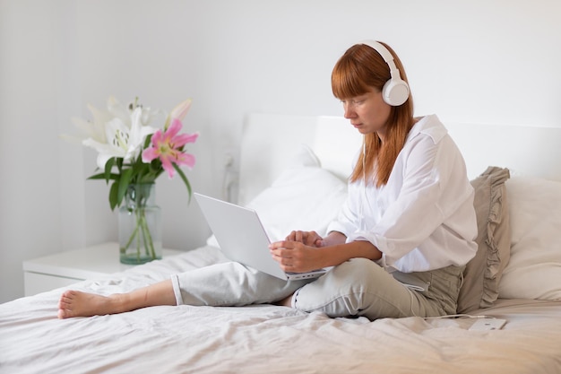 Foto gratuita niña joven, escuchar música, en cama, flor, lirio, interior