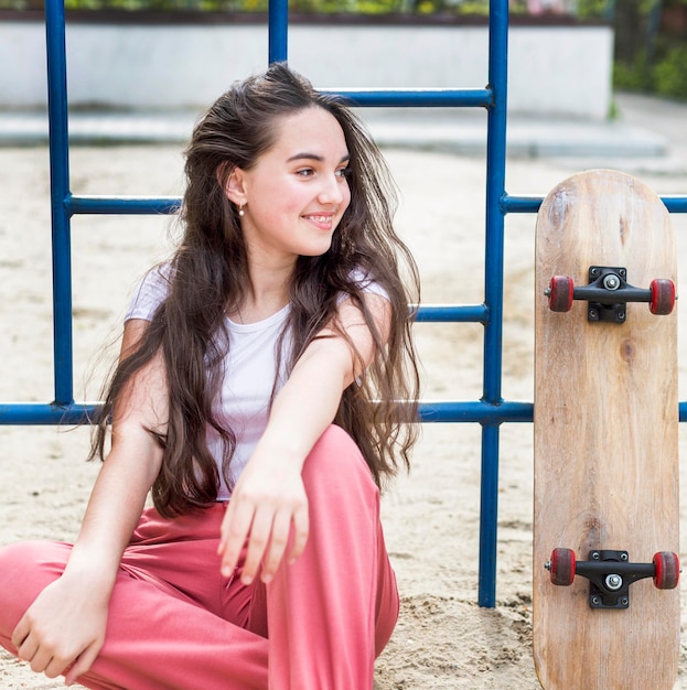 Foto gratuita niña joven, sentado, al lado de, patineta