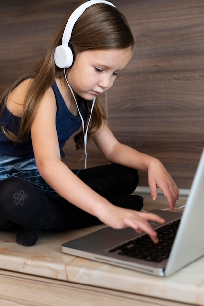 Foto gratuita niña joven, usar la computadora portátil, con, auriculares