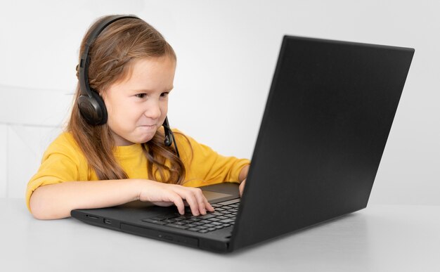 Niña joven, usar la computadora portátil, con, auriculares