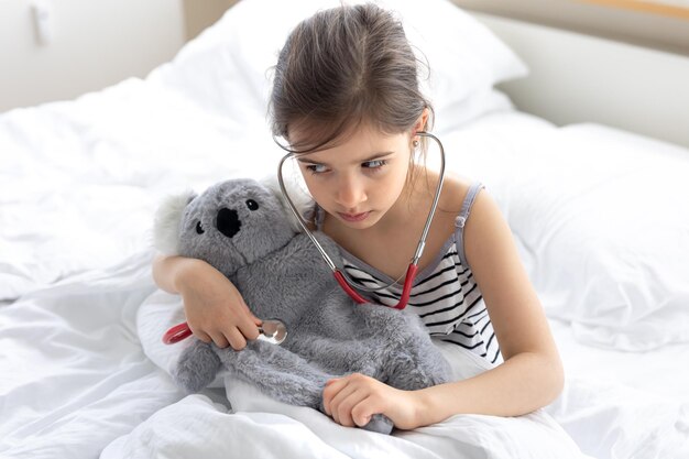 Una niña juega al doctor con su peluche favorito