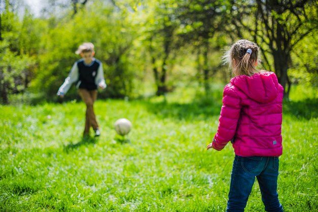 Niña jugando al fútbol con su hermano