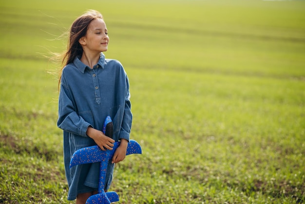 Niña jugando con avión de juguete en el campo