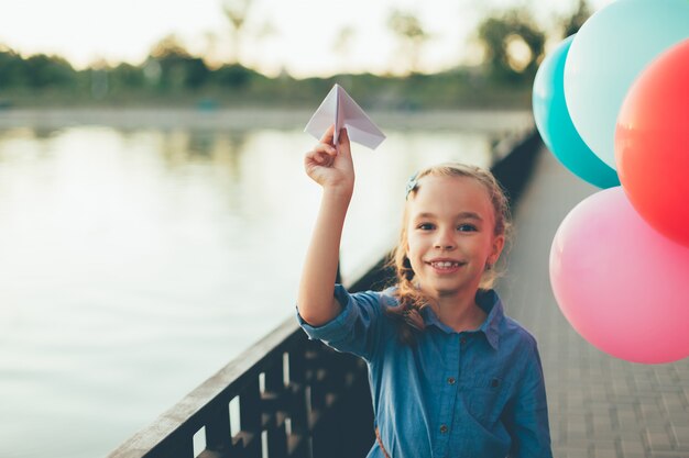 Niña jugando con avión de papel de juguete