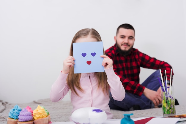 Niña jugando con una cara hecha de corazones