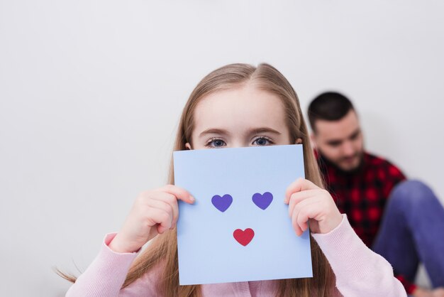 Niña jugando con una cara hecha de corazones