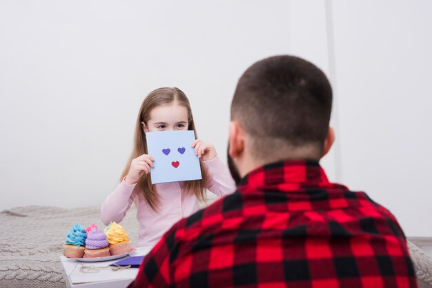 Niña jugando con una cara hecha de corazones